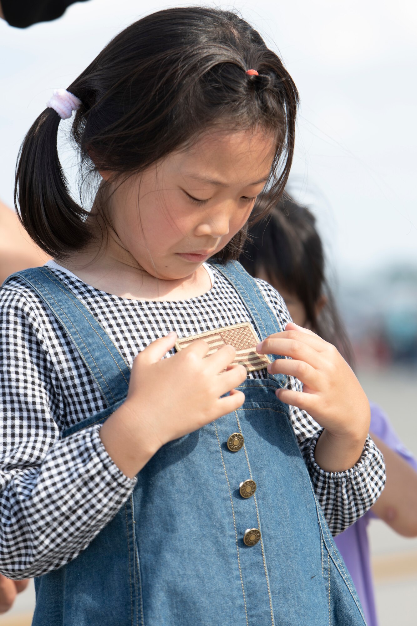 An attendee puts on an American flag badge during Friendship Festival 2022, at Yokota Air Base, Japan, May 22. The two-day festival was an opportunity for visitors to learn more about the U.S. and Japan bilateral partnership, while strengthening the bonds between Yokota and the local communities. Yokota was able to host the event with the support of Japanese Self-Defense Force, sister services and the local community. (U.S. Air Force photo by Tech. Sgt. Joshua Edwards)