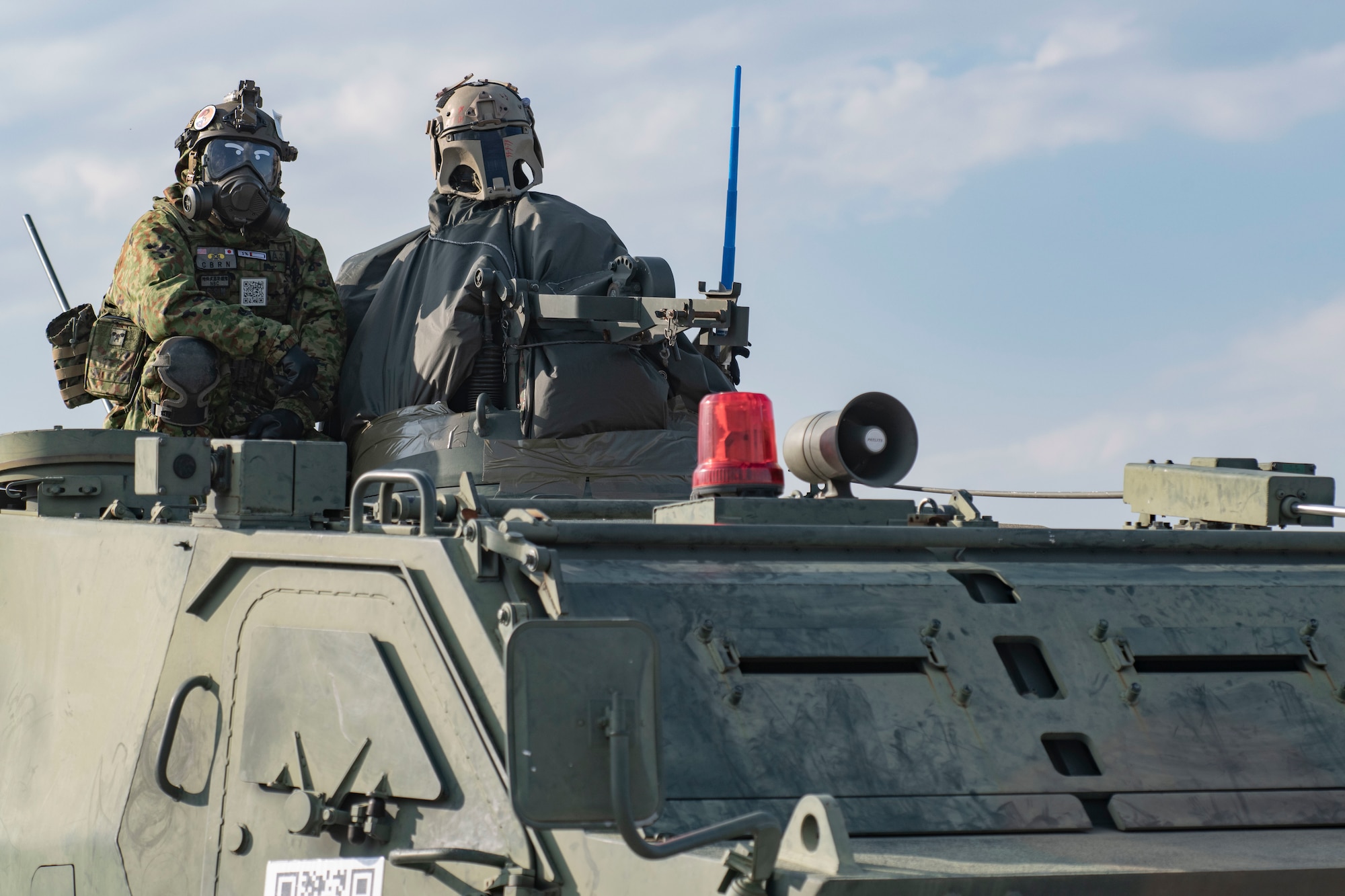 A Japan Ground Self-Defense Force member in protective gear gestures to the crowd from atop an armored personnel carrier during Friendship Festival 2022, at Yokota Air Base, Japan, May 22, 2022. The two-day festival was an opportunity for visitors to learn more about the U.S. and Japan bilateral partnership, while strengthening the bonds between Yokota and the local communities. Yokota was able to host the event with the support of Japan Self-Defense Force, sister services and the local community. (U.S. Air Force photo by Machiko Arita)