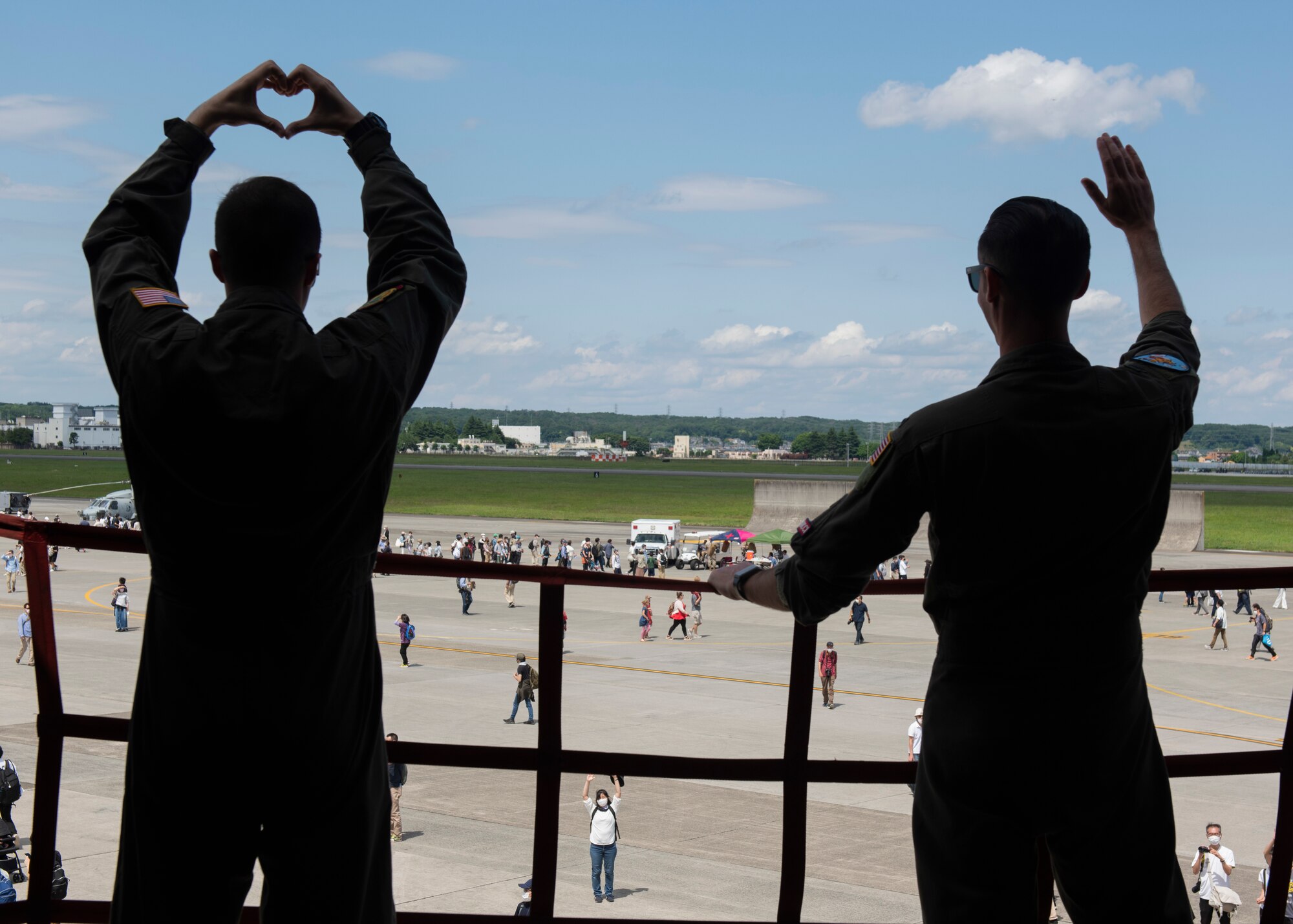 Airman 1st Class Robert Carswell, 9th Air Refueling Squadron flight engineer, left, and 1st Lt. Nathan Tomlin, 9th Air Refueling Squadron KC-10 pilot, wave to attendees during Friendship Festival 2022, at Yokota Air Base, Japan, May 22. The two-day festival was an opportunity for visitors to learn more about the U.S. and Japan bilateral partnership, while strengthening the bonds between Yokota and the local communities. Yokota was able to host the event with the support of Japan Self-Defense Force, sister services and the local community. (U.S. Air Force photo by Machiko Arita)