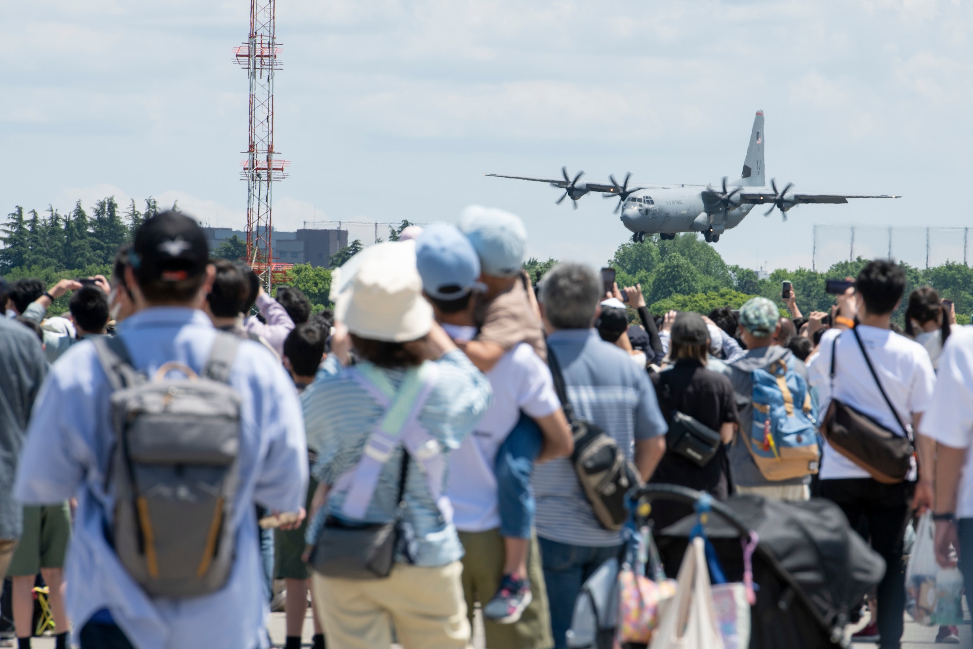 Attendee look on as a C-130J Super Hercules lands during Friendship Festival 2022, at Yokota Air Base, Japan, May 22. The two-day festival was an opportunity for visitors to learn more about the U.S. and Japan bilateral partnership, while strengthening the bonds between Yokota and the local communities. Yokota was able to host the event with the support of Japan Self-Defense Force, sister services and the local community. (U.S. Air Force photo by Machiko Arita)