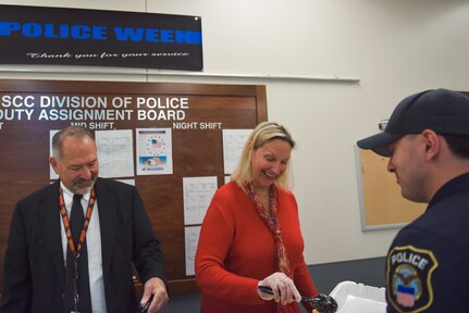 A man in a suit and a woman in red serve food to a police officer.