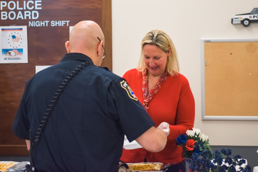 A woman in red serves food to a police officer.