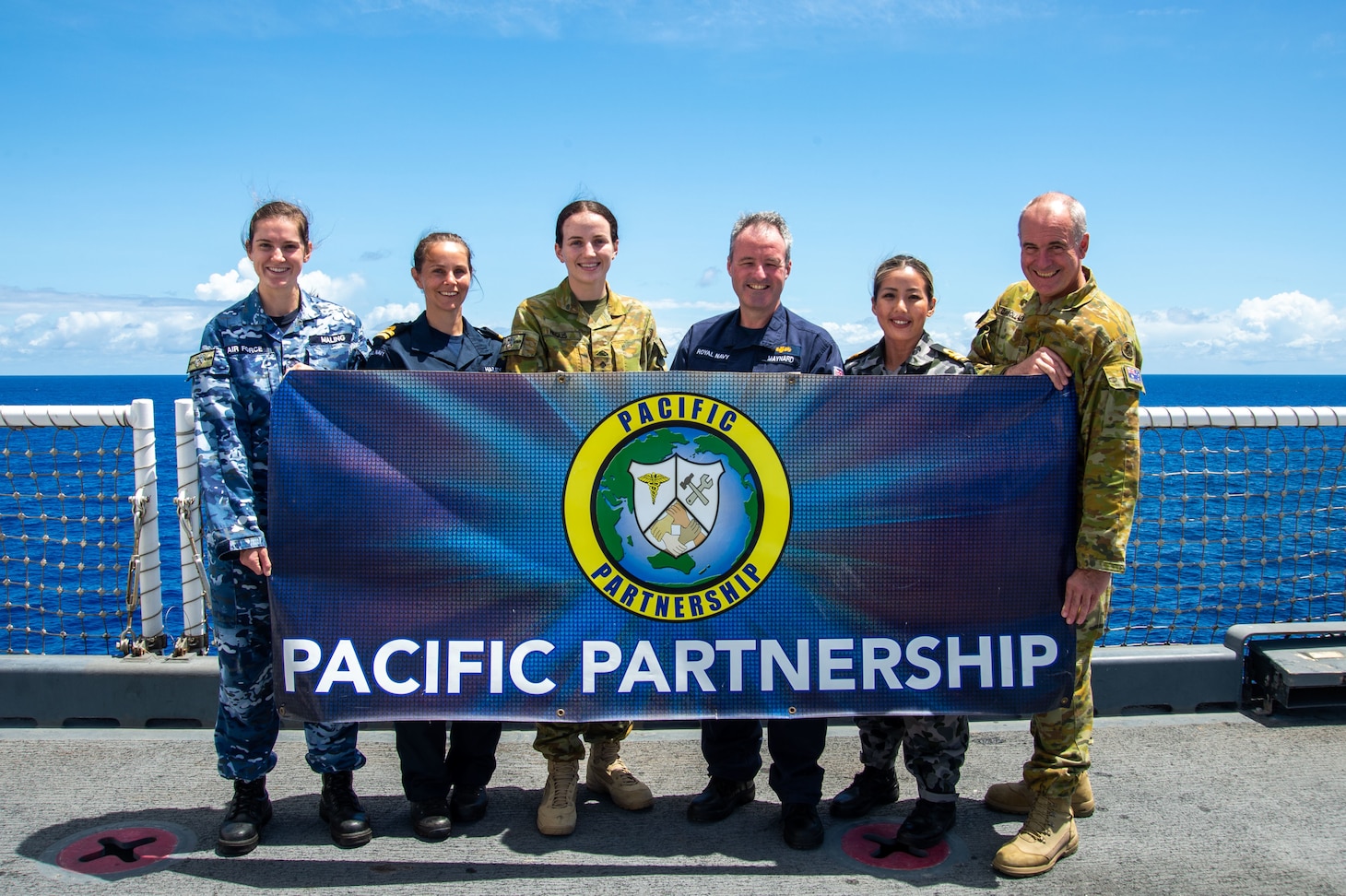 PACIFIC OCEAN (May 17, 2022) – Royal Navy and Australian Defence Force personnel pose for a photo on the flight deck aboard Military Sealift Command hospital ship USNS Mercy (T-AH 19). Mercy is currently underway as part of Pacific Partnership 2022. Now in its 17th year, Pacific Partnership is the largest annual multinational humanitarian assistance and disaster relief preparedness mission conducted in the Indo-Pacific. (U.S. Navy photo by Mass Communication Specialist 2nd Class Jacob Woitzel)