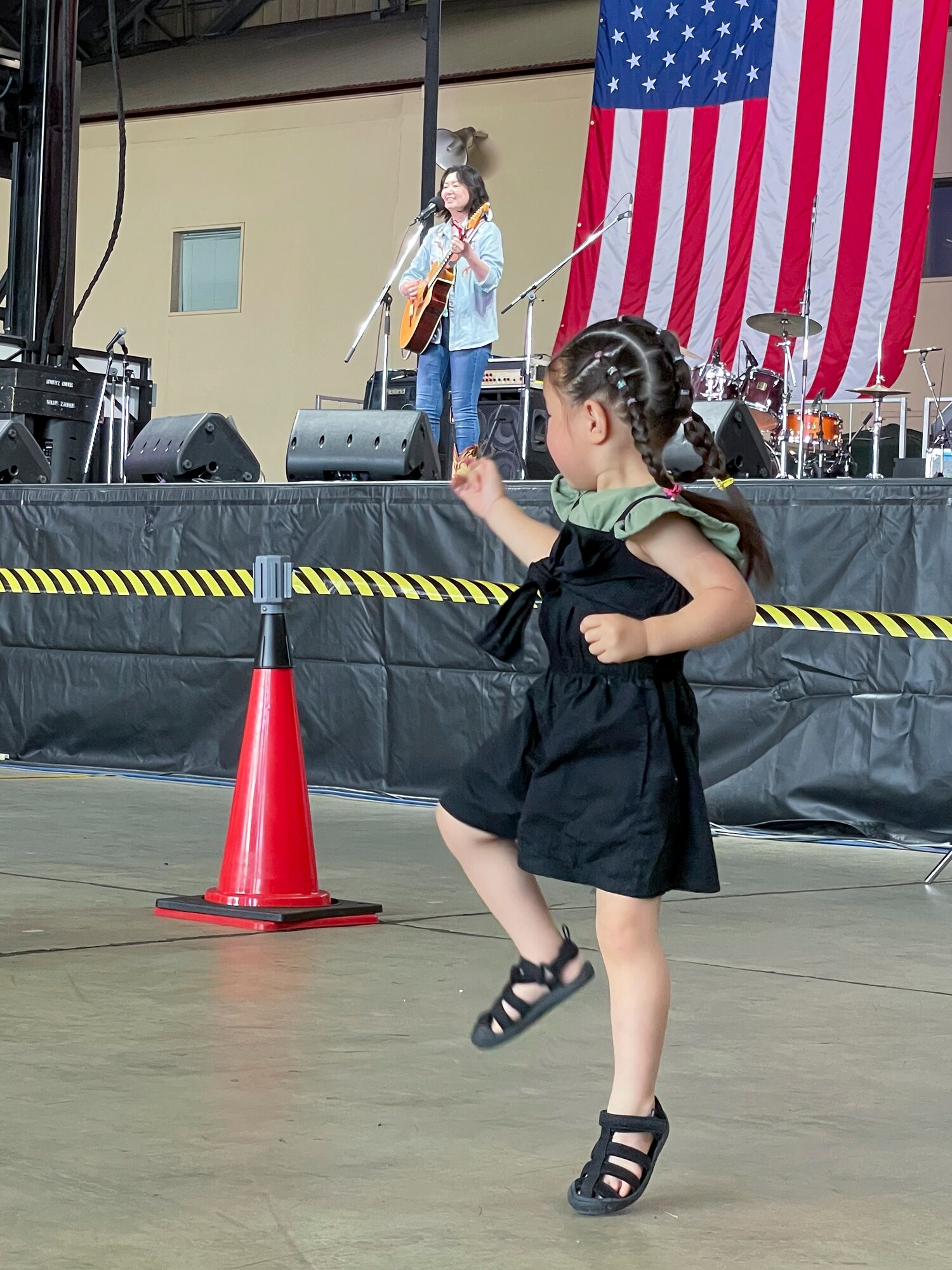 A Japanese country singer performs at the main stage while a young festival attendee dances during Friendship Festival 2022, at Yokota Air Base, Japan, May 22, 2022. The two-day festival was an opportunity for visitors to learn more about the U.S. and Japan bilateral partnership, while strengthening the bonds between Yokota and the local communities. Yokota was able to host the event with the support of Japan Self-Defense Force, sister services and the local community. (U.S. Air Force photo by Staff Sgt. Ryan Lackey)