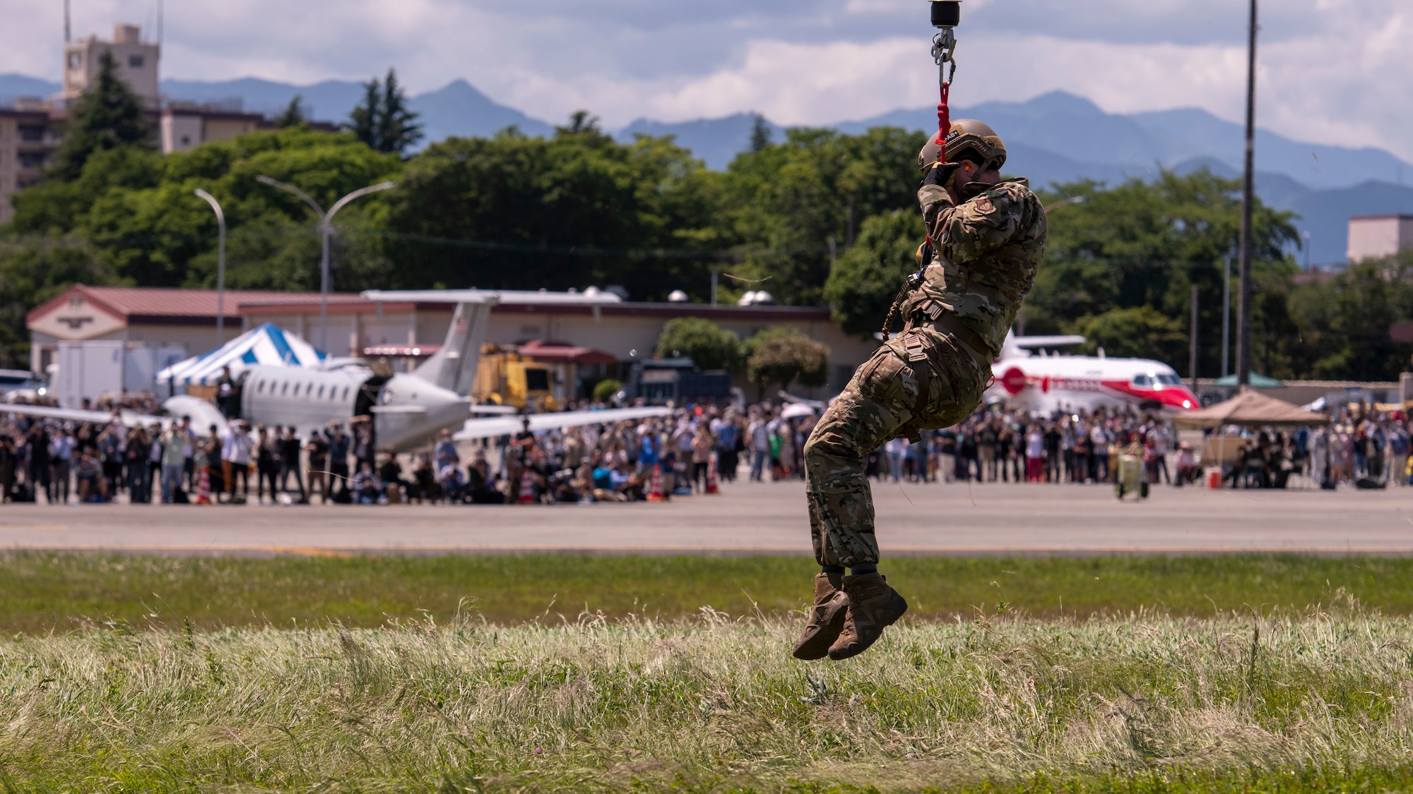 Tech. Sgt. Mark Rosenboom, 374th Operational Support Squadron Survival Evasion Resistance Escape specialist, descends to the ground during a UH-1 rescue demonstration at the Friendship Festival 2022, at Yokota Air Base, Japan, May 22, 2022. The two-day festival was an opportunity for visitors to learn more about the U.S. and Japan bilateral partnership, while strengthening the bonds between Yokota and the local communities. Yokota was able to host the event with the support of Japan Self-Defense Force, sister services and the local community. (U.S. Air Force photo by Staff Sgt. Ryan Lackey)