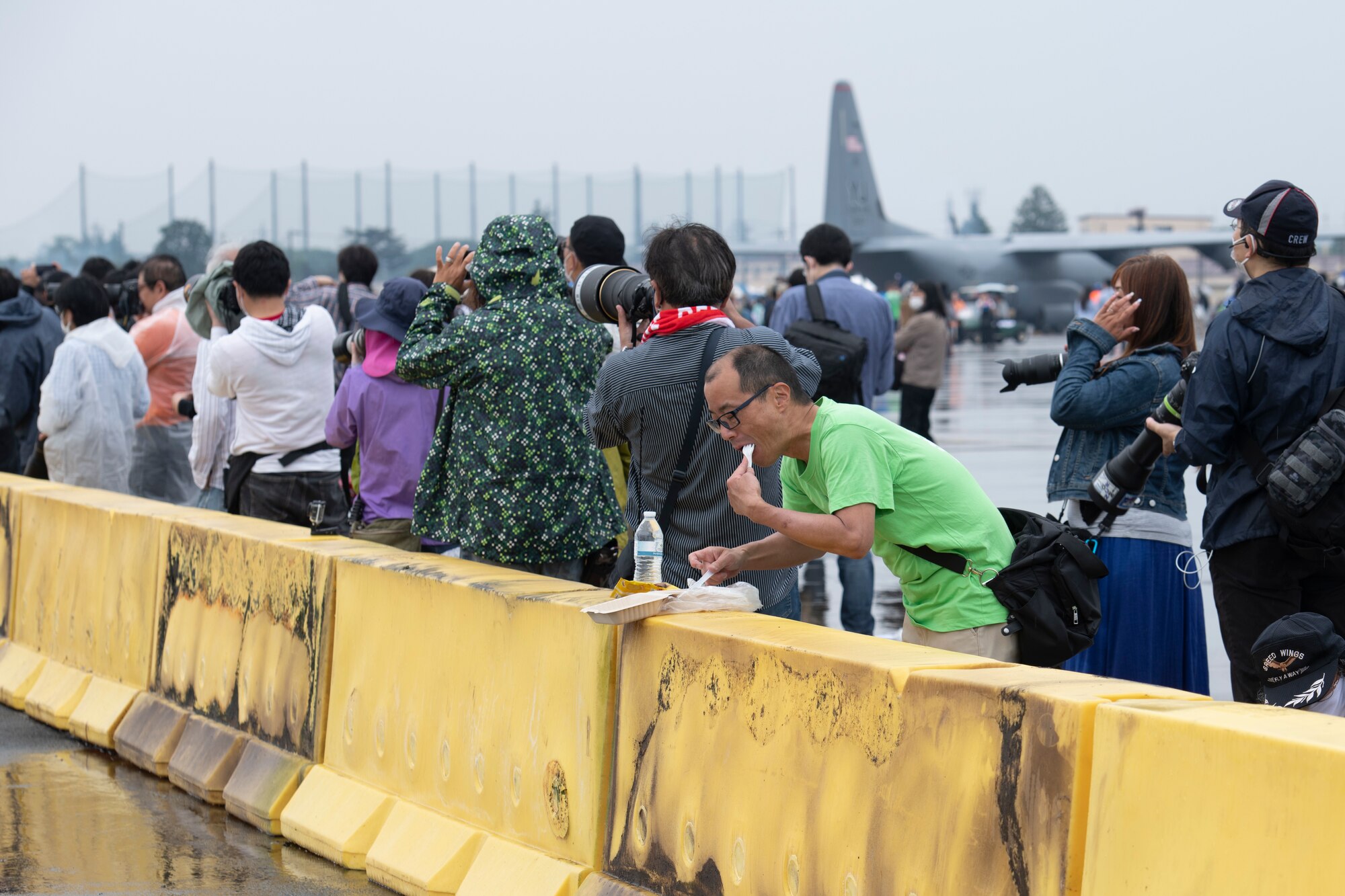 An attendee eats food while an F-16 Fighting Falcon flies by during Friendship Festival 2022, at Yokota Air Base, Japan, May 21. The two-day festival was an opportunity for visitors to learn more about the U.S. and Japan bilateral partnership, while strengthening the bonds between Yokota and the local communities. Yokota was able to host the event with the support of Japan Self-Defense Force, sister services and the local community. (U.S. Air Force photo by Tech. Sgt. Joshua Edwards)