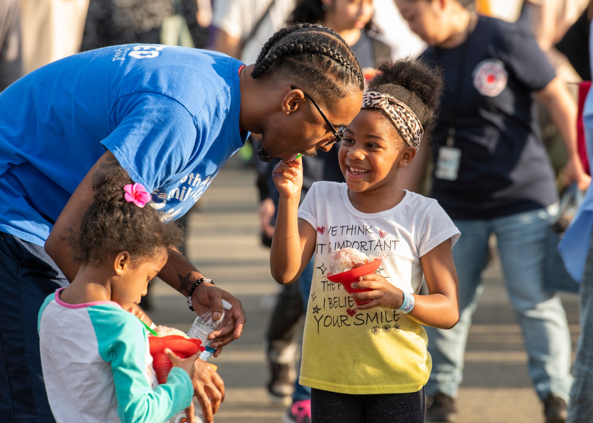 A child feeds water ice to her father.