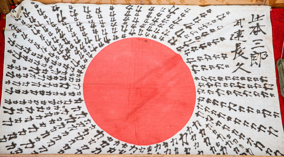 “Chikara” flag. This type of flag is a Chikara flag due to the repeated kanji which reads “Chikara” meaning power. The Kanji in the upper right hand corner reads Okamoto Saburo which is the owner’s name. The second line from the right reads Bunchokyu which translates to good luck in battle. This flag was picked up during the Battle of Okinawa by a 6th Marine Division veteran.