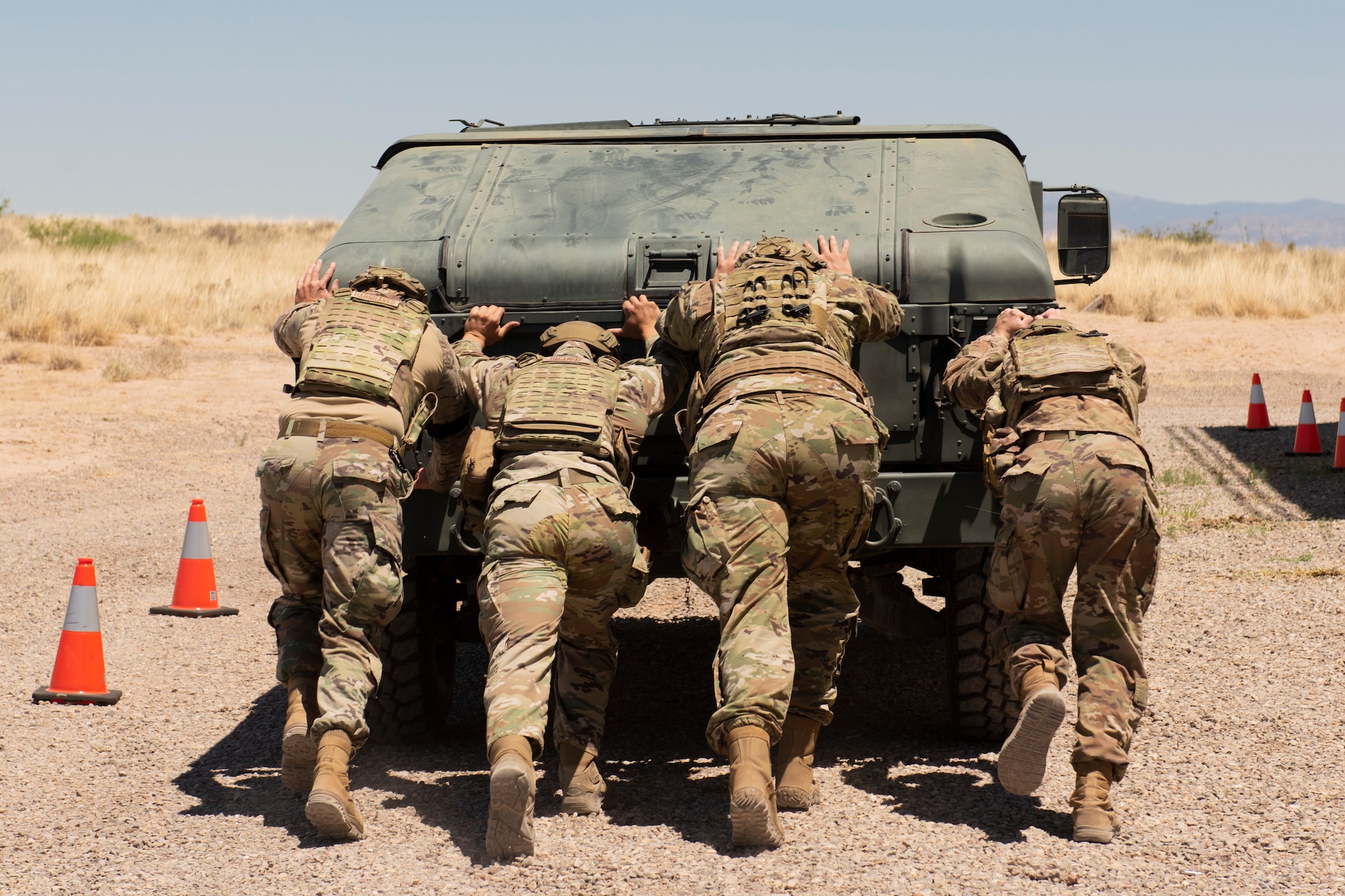 Members of the 49th Security Forces Squadron push a military vehicle during  the Defender Challenge at the Security Forces Training Complex May 11, 2022, on Holloman Air Force Base, New Mexico. The course consisted of a series of challenges that tested both the mental and physical aspects required to be a Defender. (U.S. Air Force photo by Airman Isaiah Pedrazzini)