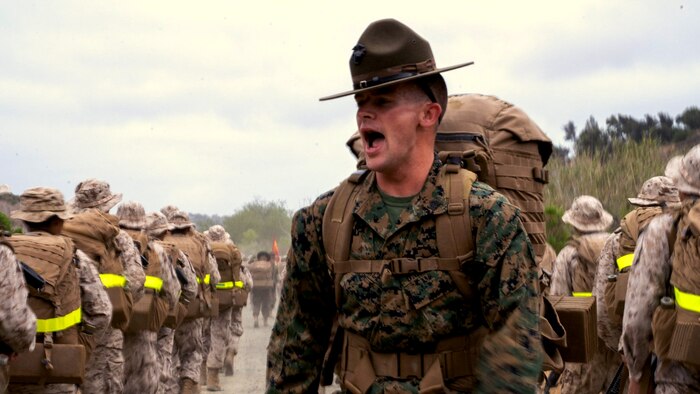 A U.S. Marine Corps drill instructor with Lima Company, 3rd Recruit Training Battalion, motivates recruits during a 5-kilometer hike during grass week at Marine Corps Base Camp Pendleton, California, May 17, 2022