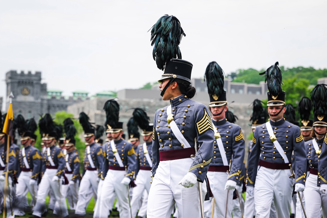 Army cadets march in formation on a field.