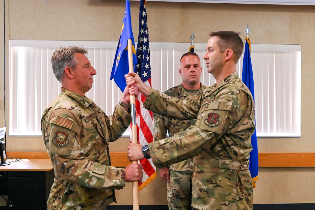 167th Operations Group deputy commander Lt. Col. John McCullough presents 167th Operations Support Squadron commander (OSS) Lt. Col. James Holsinger with the guidon during the OSS change of command ceremony held at the 167th base dining facility, Martinsburg, West Virginia, May 14, 2022. Air Force change of command ceremonies are a time-honored tradition where incoming commanders officially assume command while their airmen bear witness.