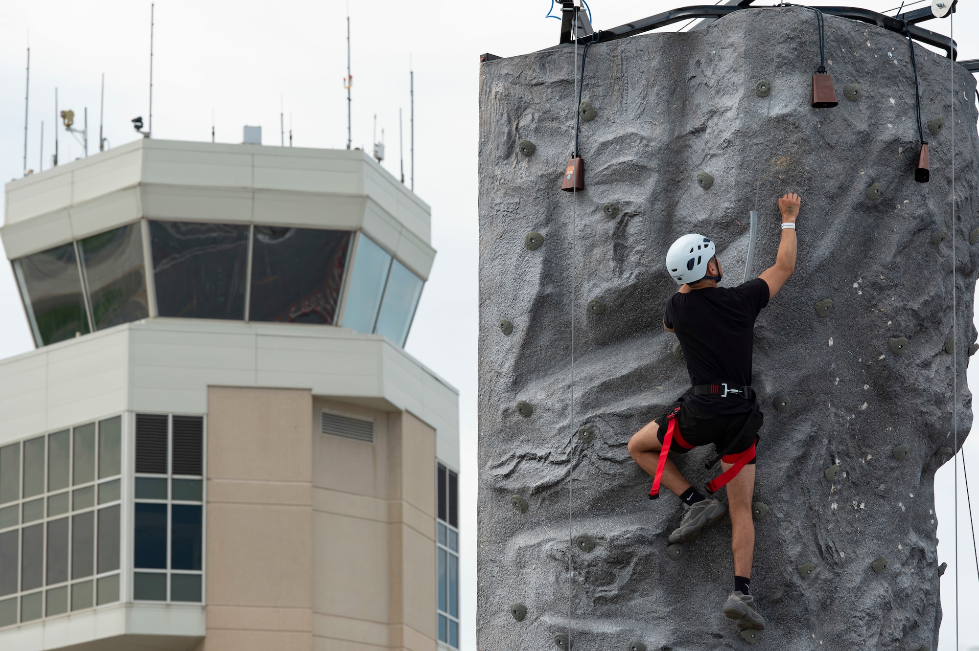 Yeshua Martinez, from Northfield, New Jersey, climbs up the rock wall during the second day of the 2022 Thunder Over Dover Airshow at Dover Air Force Base, Delaware, May 21, 2022. The airshow’s theme was “Reunite,” in celebration of people coming together after the COVID-19 pandemic. (U.S. Air Force photo by Roland Balik)