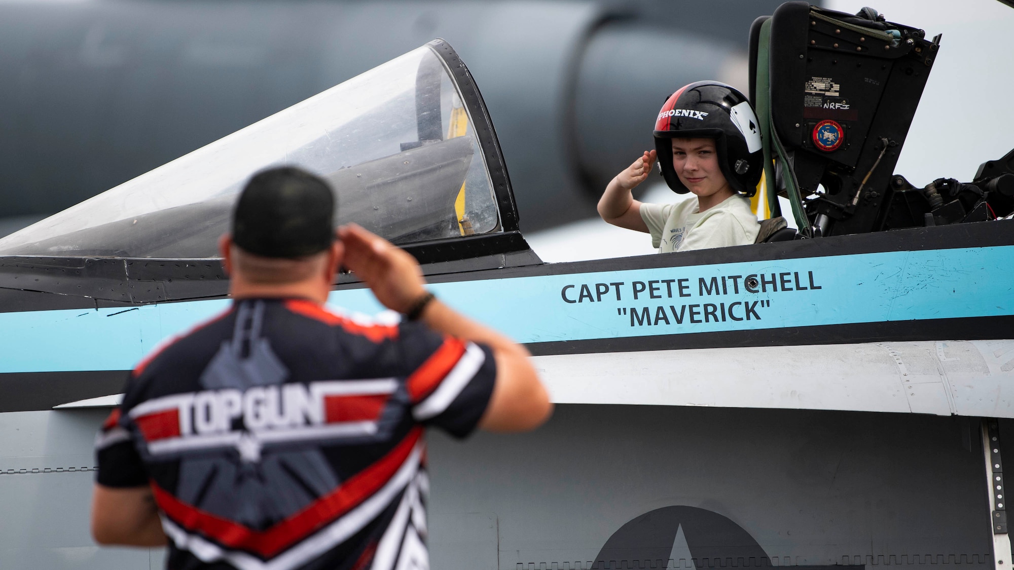 A spectator salutes while in a F-18 simulator during the 2022 Thunder Over Dover Airshow, May 22, 2022, at Dover Air Force Base, Delaware. The event was the first airshow and open house held at Dover AFB since September 2019. (U.S. Air Force photo by Tech. Sgt. J.D. Strong II)