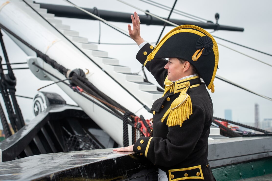 Cmdr. B.J. Farrell, Commanding Officer of USS Constitution, waves after a 21-Gun Salute during an underway aboard Constitution.