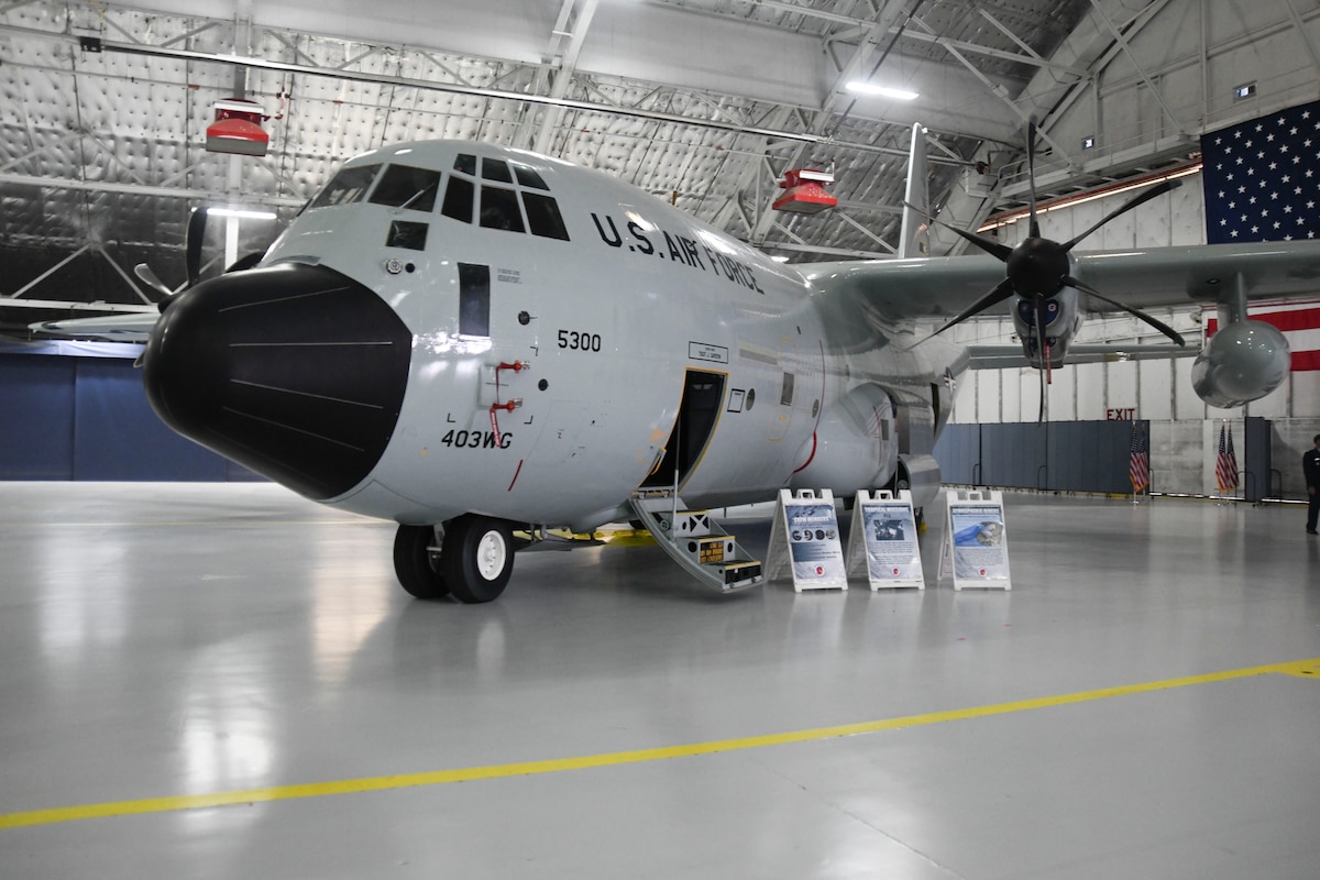 A WC-130J is parked in an enclosed aircraft hangar