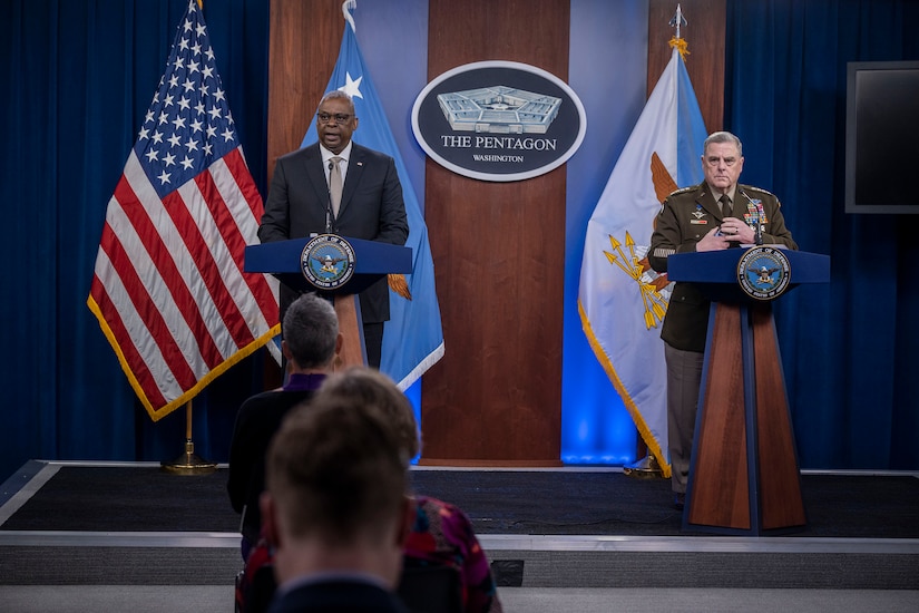 Defense secretary and Joint Chiefs chairman stand at twin lecterns in front of seated audience.
