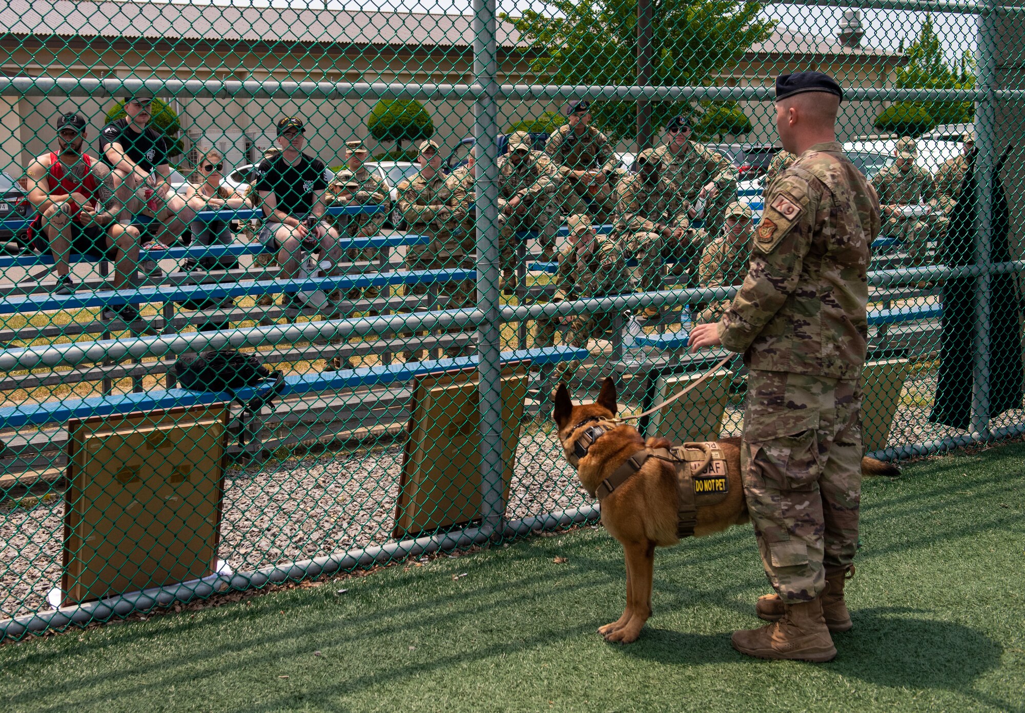 Staff Sgt. Russell Postmus, 8th Security Forces Squadron Military Working Dog handler, and MWD Ricky, address the crow before a display during Police Week 2022 at Kunsan Air Base, Republic of Korea, May 18, 2022. MWD displays help educate the base about the dangers of disobeying the commands of defenders. (U.S. Air Force Photo by Tech. Sgt. Timothy Dischinat)
