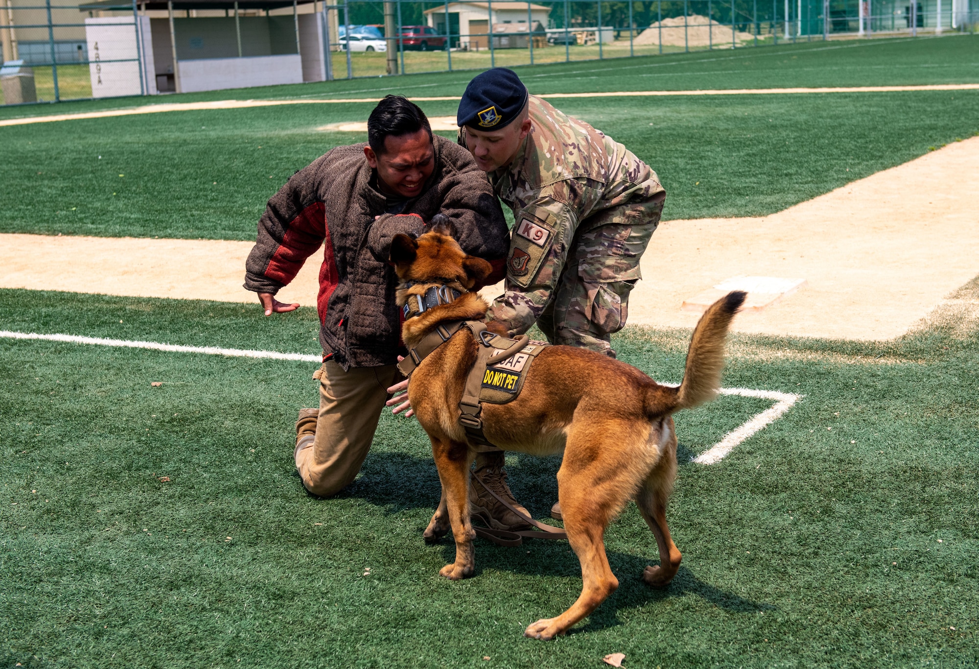 Senior Airman Fc Beltran simulates disobeying the commands of Staff Sgt. Russell Postmus, both 8th Security Forces Squadron Military Working Dog handlers, as they conduct a display with MWD Ricky, during Police Week 2022 at Kunsan Air Base, Republic of Korea, May 18, 2022. During this week, Airmen from the 8th Fighter Wing participated in a myriad of activities to pay tribute to fallen law enforcement officers; to include a memorial run, rifle competition, relay challenge and observing the MWD demo. (U.S. Air Force Photo by Tech. Sgt. Timothy Dischinat)