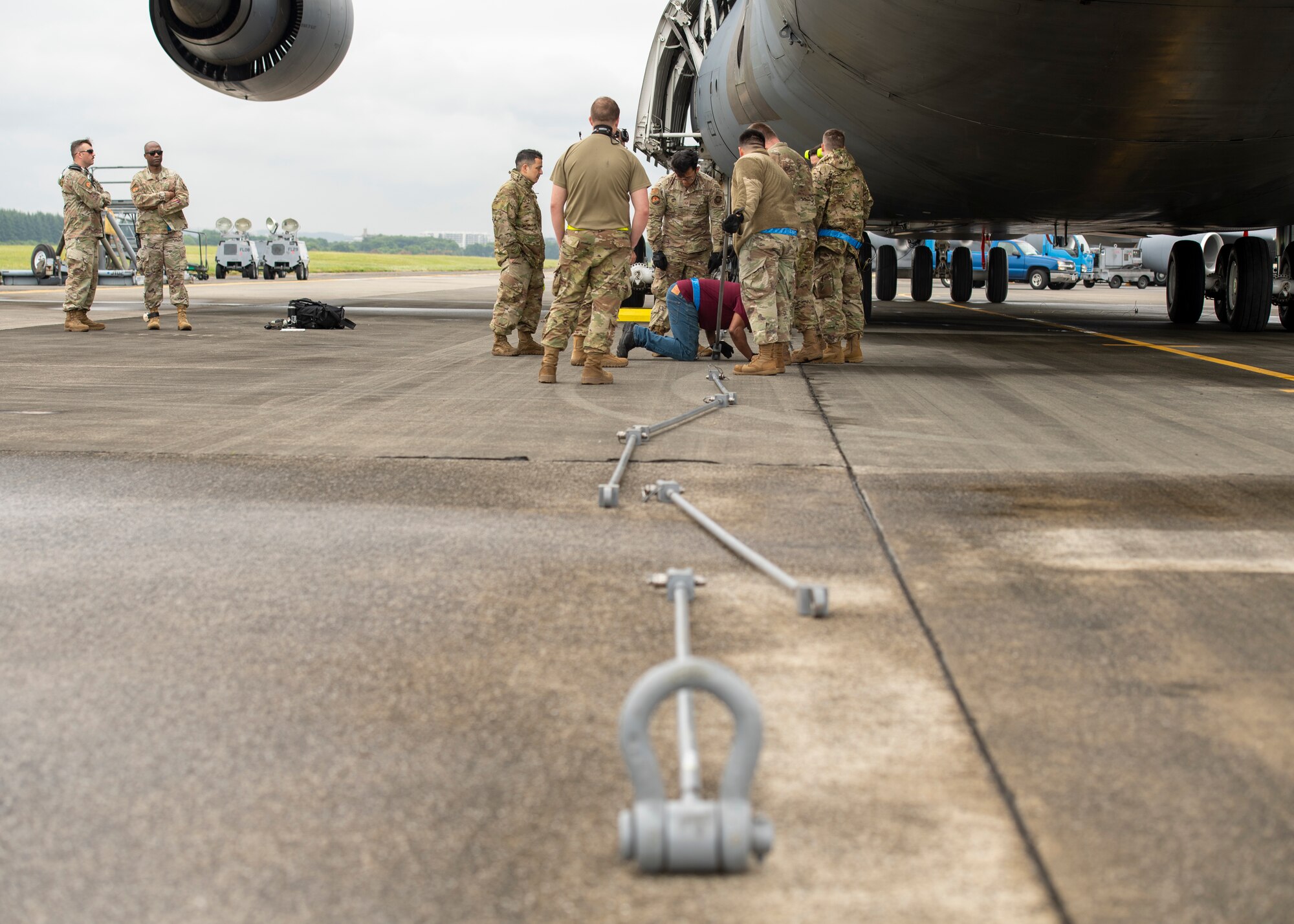 A wide view of eight airmen attaching metal bars together