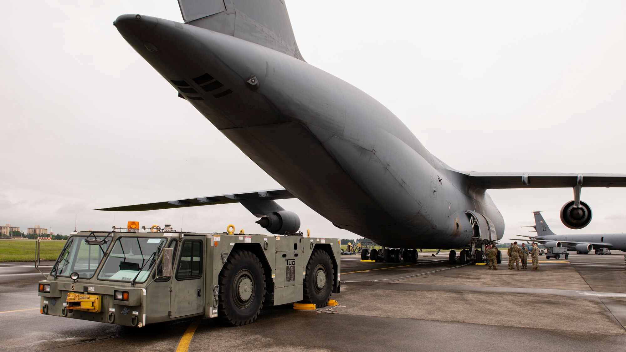 A back view of a large cargo aircraft and a tow truck