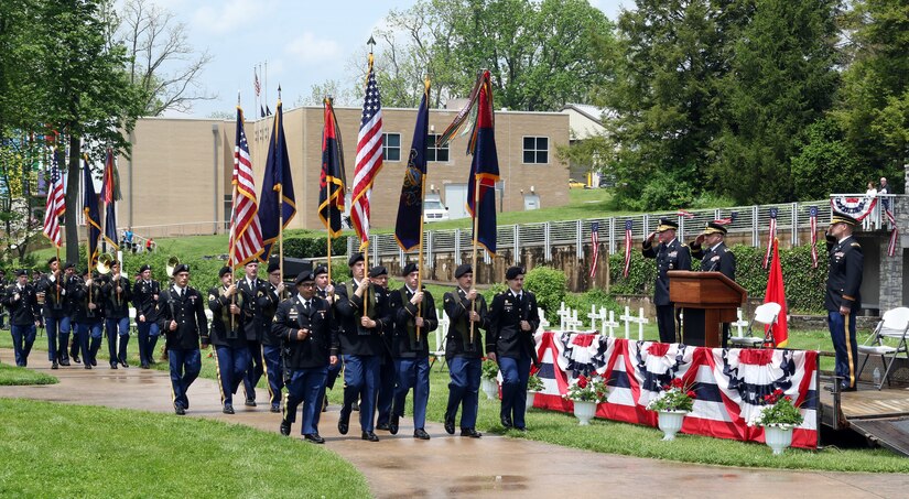 Soldiers of the 28th Infantry Division move the unit's colors to the division shrine at Boalsburg for the annual memorial service on May 22, 2022. Saluting on the reviewing stand, from left, are Maj. Gen. Mark Schindler, Pa. Adjutant General; Maj. Gen. Mark McCormack, division commander; and Lt. Col. Ryan Kraus, division chaplain.