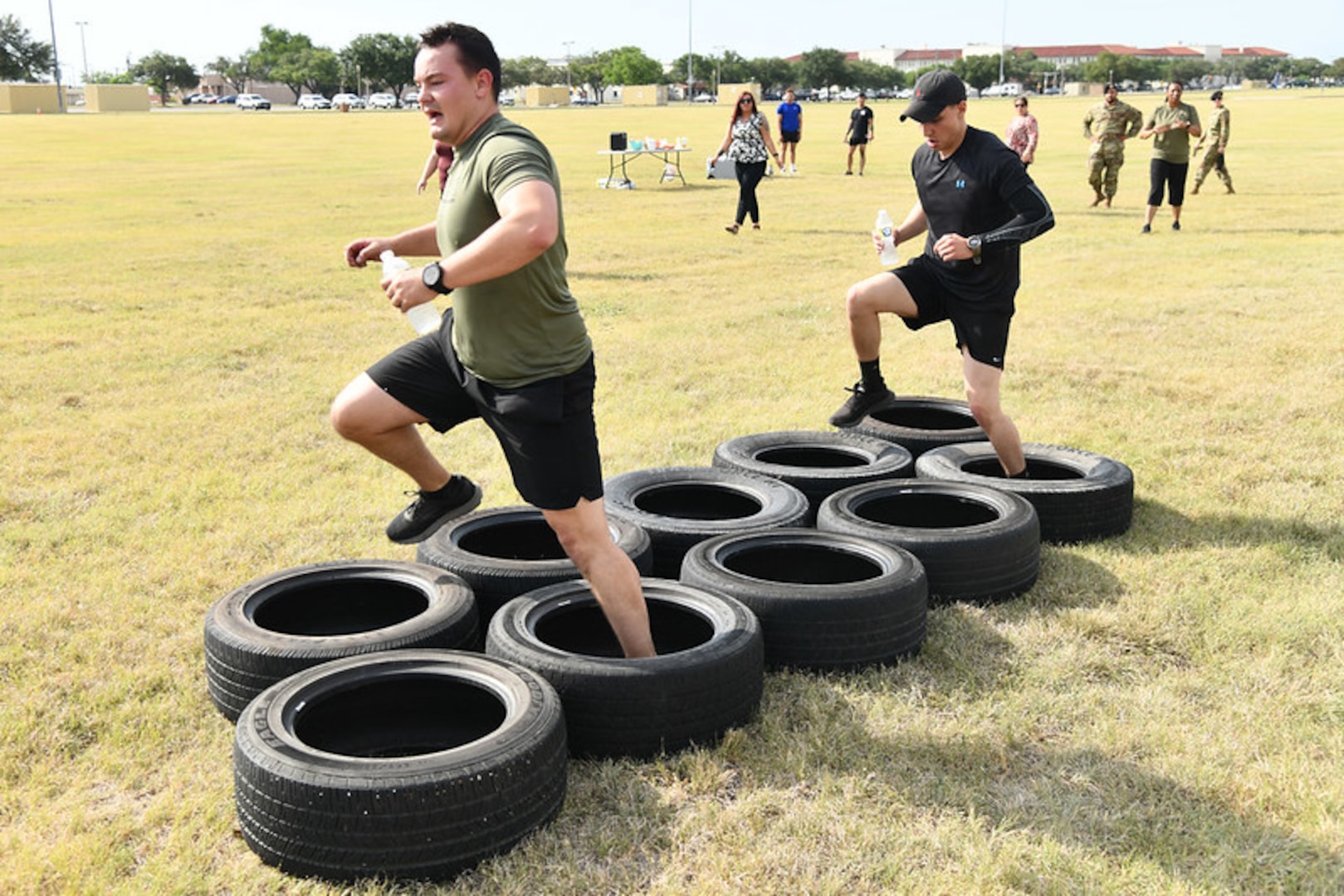 Two men stepping through tires.