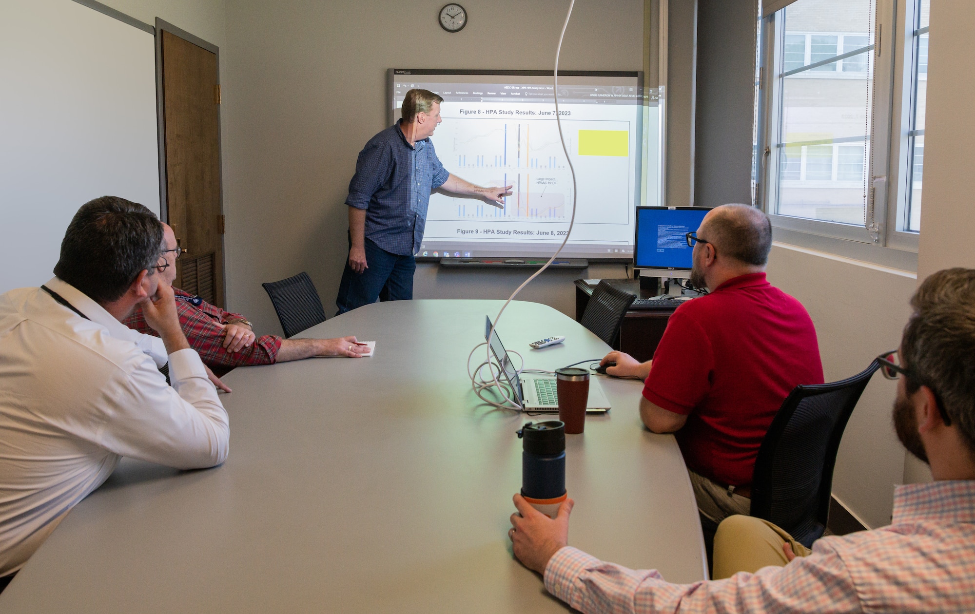 Greg Sterling, an aerospace engineer with Arnold Engineering Development Complex (AEDC), reviews some of his findings in his work on the Scenario Optimizer for AEDC Resources (SOAR) with fellow AEDC team members, May 11, 2022, at Arnold Air Force Base, Tenn. SOAR is a software application for comparing different test schedules based on test user requirements to identify high-pressure air restrictions or limitations. (U.S. Air Force photo by Jill Pickett) (This image has been altered by obscuring a white board and portion of a screen.)