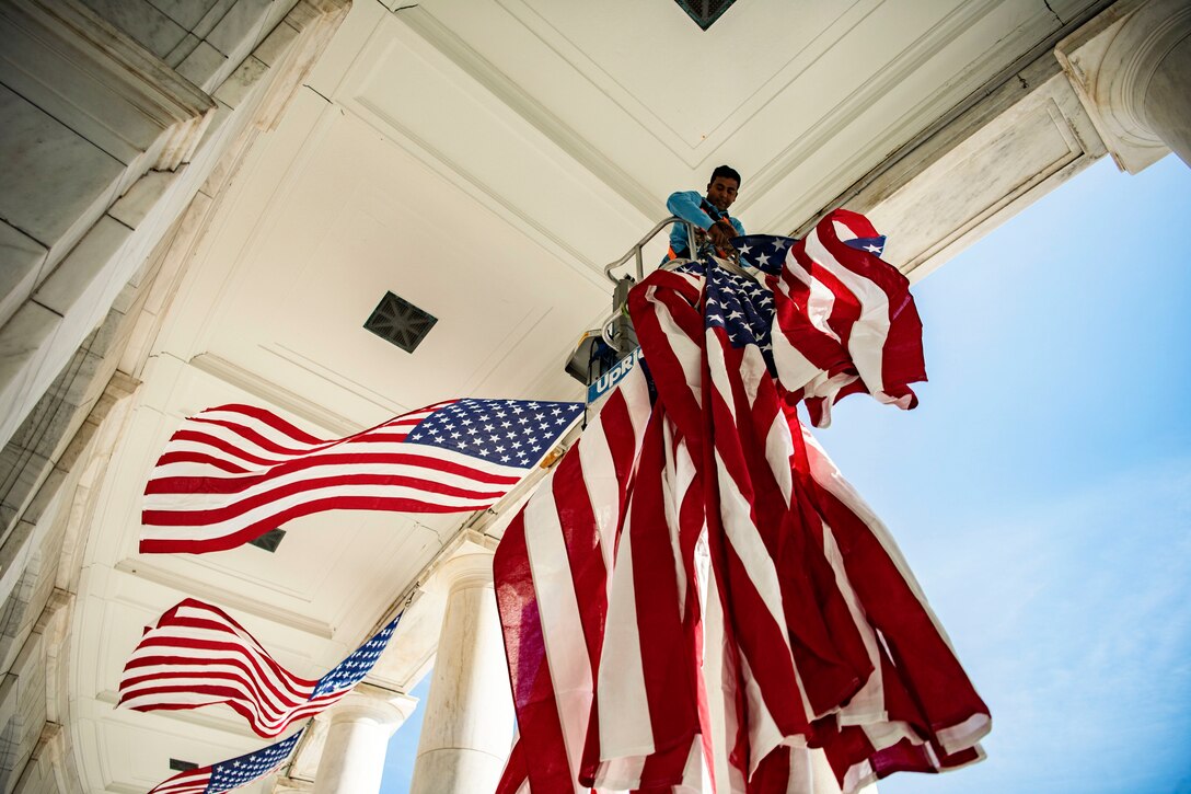 A employee hangs an American flag at Arlington National Cemetery.