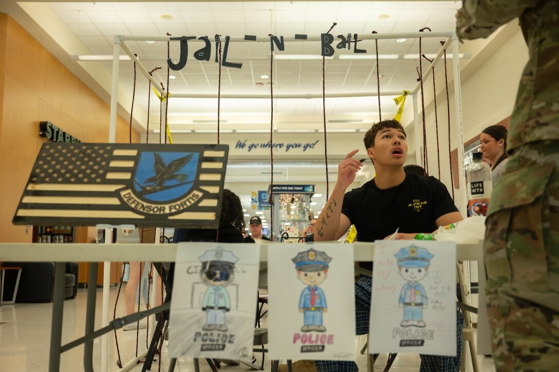 Senior Airman Charles Robinson, 21st Security Forces Squadron response force leader, explains the squadrons Jail ‘N’ Bail event to an Airman at Peterson Space Force Base, Colorado, May 18, 2022. The event was held to raise money for the Pikes Peak Peace Officer Memorial. (U.S. Space Force photo by Senior Airman Jonathan Whitely)