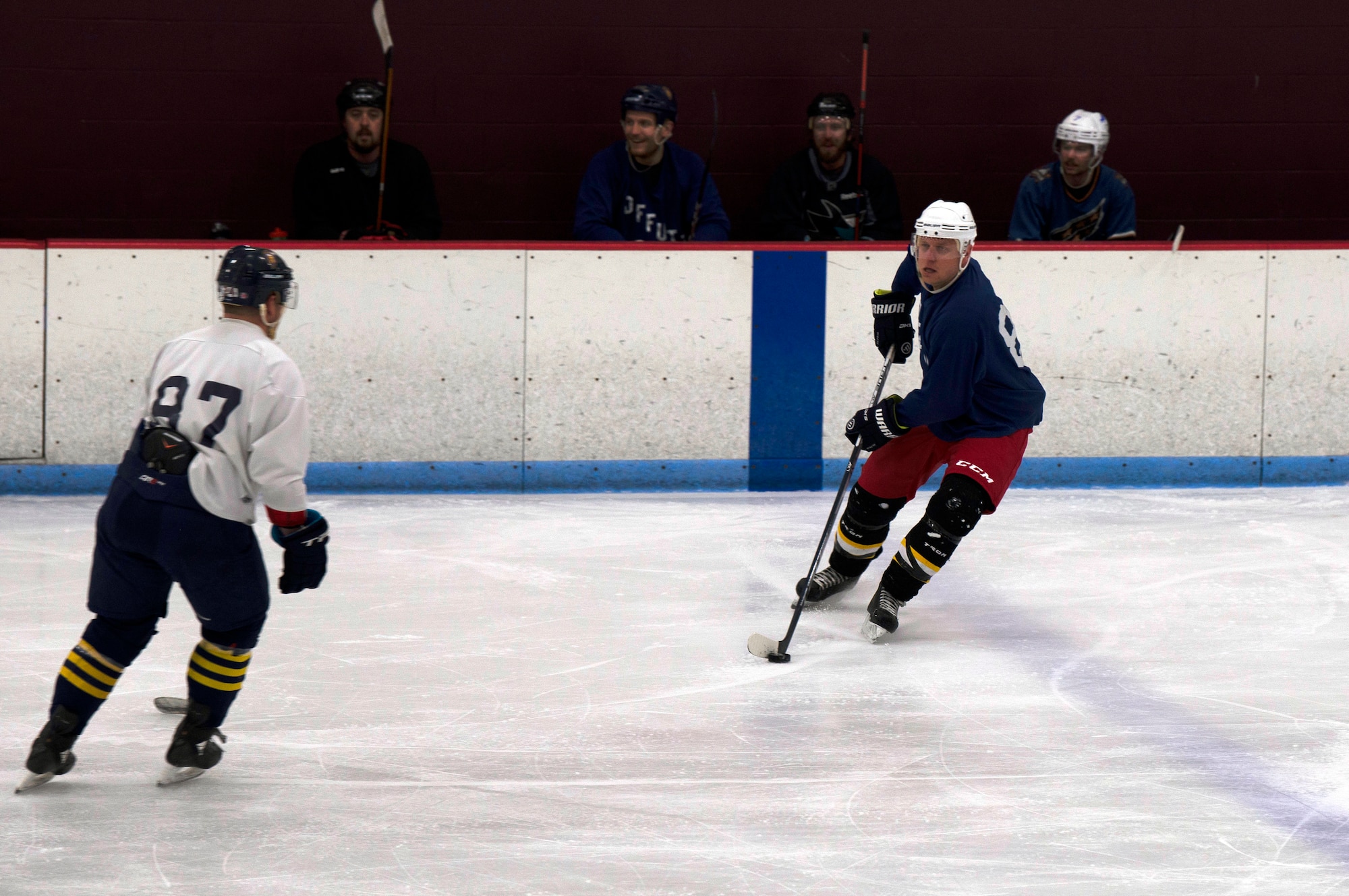 hockey player handles puck while approaching defender.