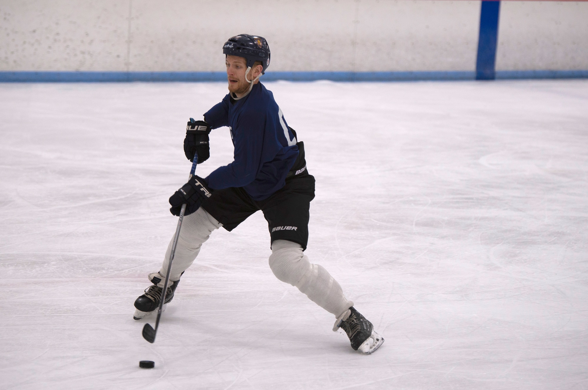 male hockey player takes a shot at a puck.