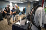 Robert Curtis, right, national sales manager for Alpha Quantix, a Los Angeles-based exoskeleton and robotics company, shows Shop 56 Pipefitters (from left) Cole Knuckey and Josh Davies how the "Ironhand" can aid a shipyard worker's grip Aug. 25, 2021, during PSNS & IMF's 2021 Technology Showcase at the Kitsap Conference Center in Bremerton, Washington. (U.S. Navy photo by Scott Hansen)