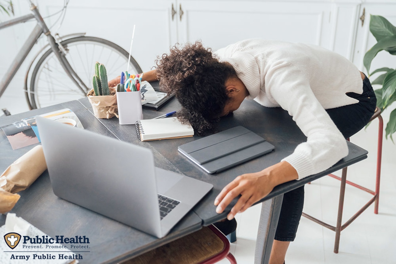 A woman lays her head on a desk.