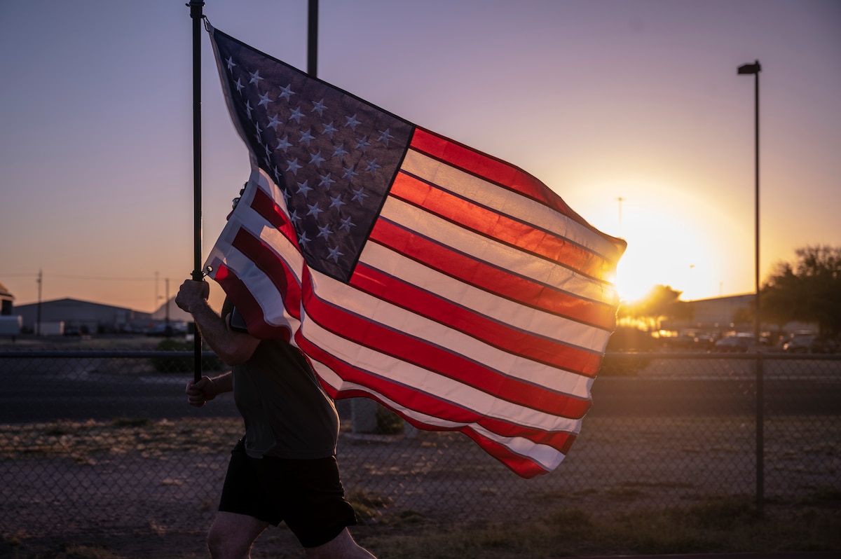A photo of an Airmen running with a flag.