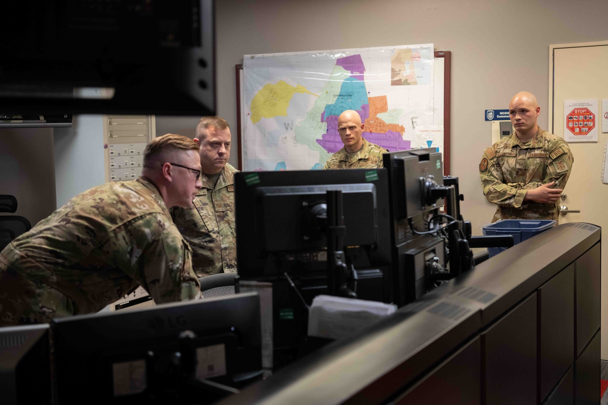 Military members stand around a computer that recieves smoke notifications.