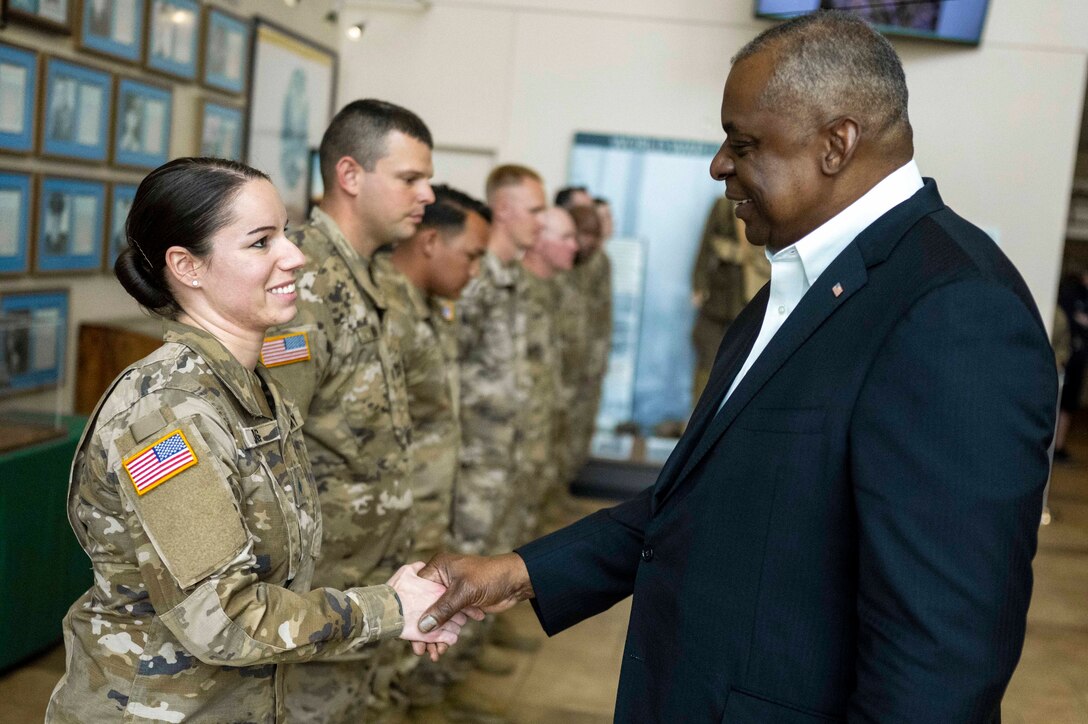 A service member standing in a line with others shakes hands with Secretary of Defense Lloyd J. Austin III.