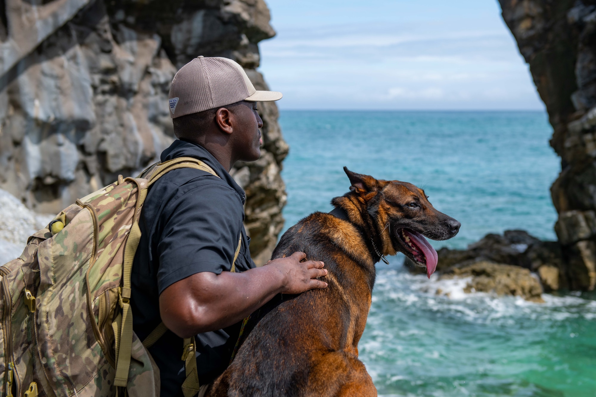 A dog and his handler look out over the ocean