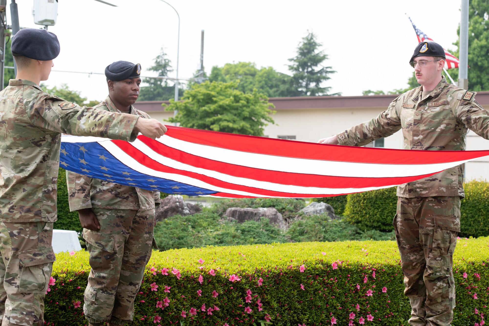 Members of 374th Security Force Squadron begin to fold the American Flag during a police retreat ceremony at Yokota Air Base, Japan, May 20, 2022. The 374th SFS held the ceremony during Police Week to honor law enforcement personnel as well as recognize the dangers and risks they face every day. (U.S. Air Force photo by Machiko Arita)