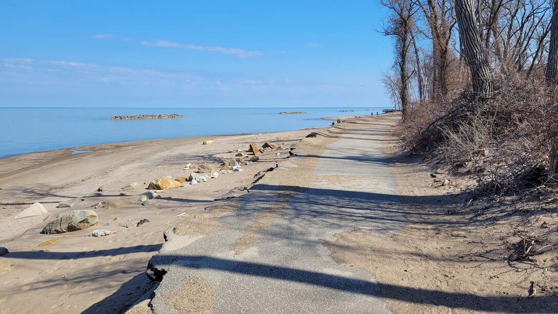 Sand and an asphalt path along a Lake Erie beach.