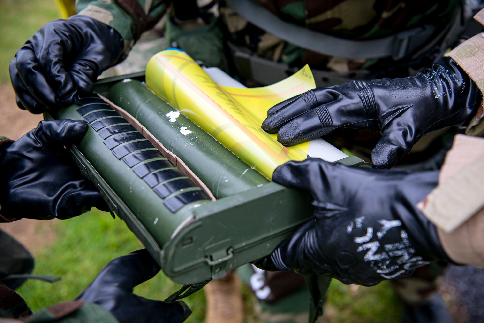 Airmen from the 423d Civil Engineer Squadron, grab a marking sign for an exercise at RAF Alconbury, England, May 19, 2022. The exercise was geared towards training Airmen on how to properly control and examine a contaminated area after a simulated chemical attack while in Mission Oriented Protective Posture Gear. (U.S. Air Force photo by Staff Sgt. Eugene Oliver)