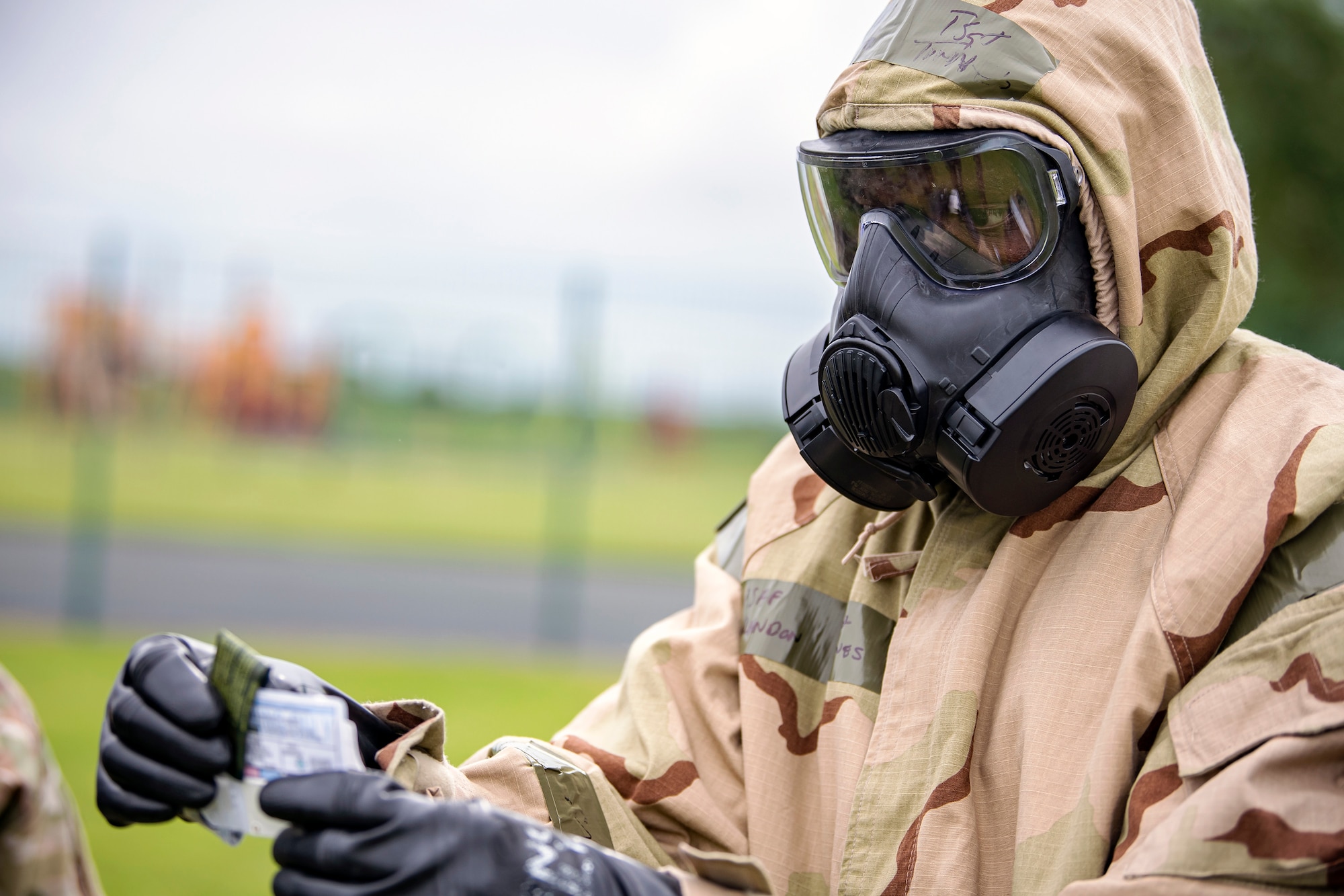 Master Sgt. Brandon Townes, left, 423d Civil Engineer Squadron section chief holds a M256 kit during an exercise at RAF Alconbury, England, May 19, 2022. The exercise was geared towards training Airmen on how to properly control and examine a contaminated area after a simulated chemical attack while in Mission Oriented Protective Posture Gear. (U.S. Air Force photo by Staff Sgt. Eugene Oliver)