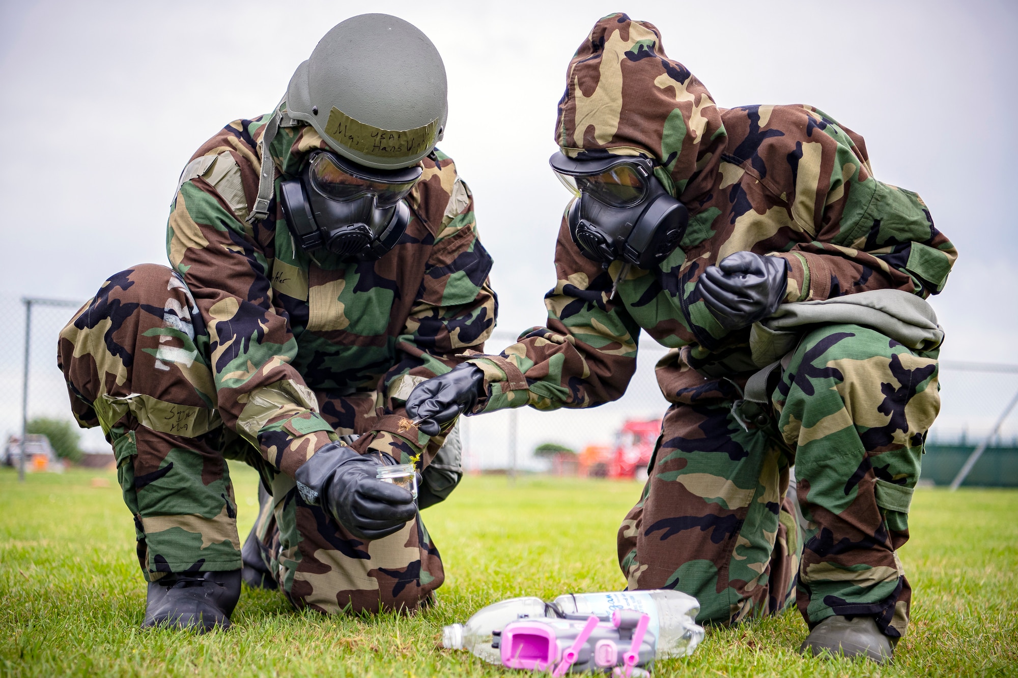 U.S. Air Force Lt. Col. Hans Winkler, left, 423d Civil Engineer Squadron commander, collects a soil sample from Staff Sgt. Naujy Serrano, right, 423d CES emergency management NCO in charge of plans and operations, during an exercise at RAF Alconbury, England, May 19, 2022. The exercise was geared towards training Airmen on how to properly control and examine a contaminated area after a simulated chemical attack while in Mission Oriented Protective Posture Gear. (U.S. Air Force photo by Staff Sgt. Eugene Oliver)