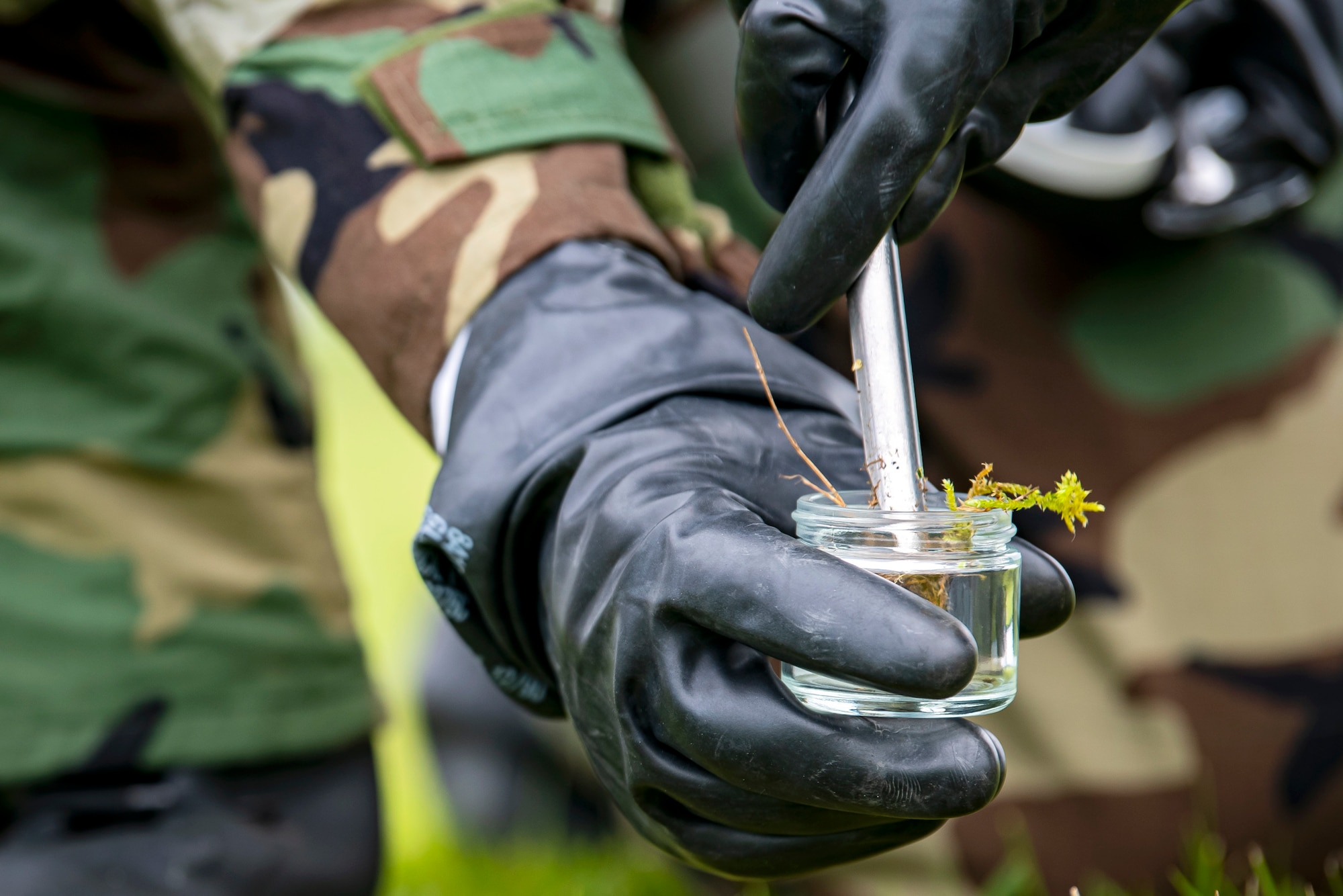 An Airman from the 423d Civil Engineer Squadron, collects a soil sample from a simulated contaminated area during an exercise at RAF Alconbury, England, May 19, 2022. The exercise was geared towards training Airmen on how to properly control and examine a contaminated area after a simulated chemical attack while in Mission Oriented Protective Posture Gear. (U.S. Air Force photo by Staff Sgt. Eugene Oliver)