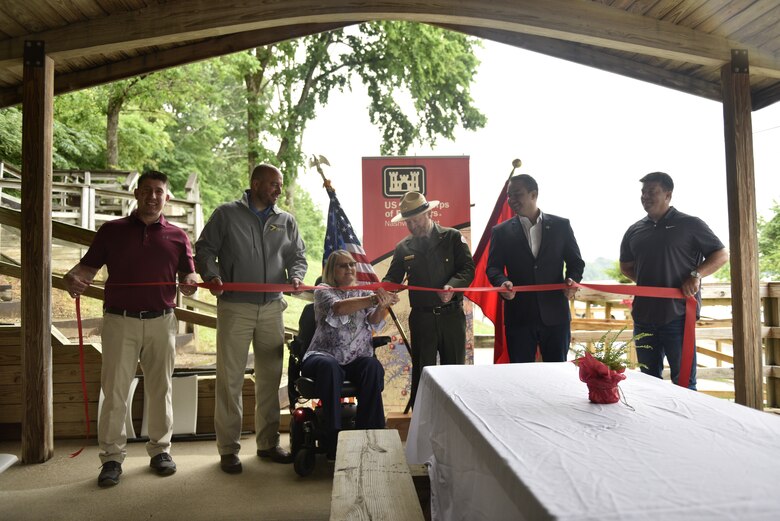 Sandy Stigall cuts the ribbon on the wheelchair access ramp on May 23, 2022, at Waitsboro Recreation Area, Somerset, Kentucky. 
Pictured from left to right – Alex Godsey AGT Engineering, Chris Girdler president and CEO of Somerset-Pulaski Economic Development Authority (SPEDA), Sandy Stigall, Lake Cumberland Resource Manager Jon Friedman, Somerset Mayor Alan Keck, and Chris Goff A&C Construction.
