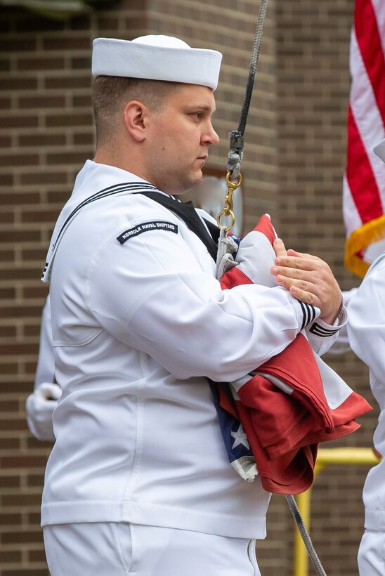 The Norfolk Naval Shipyard Flag Detail, alongside Gold Star Family Member and Veterans Employee Readiness Group member Glenn Branchaud, raises the flag during the Memorial Day Fall-In for Colors May 25.
