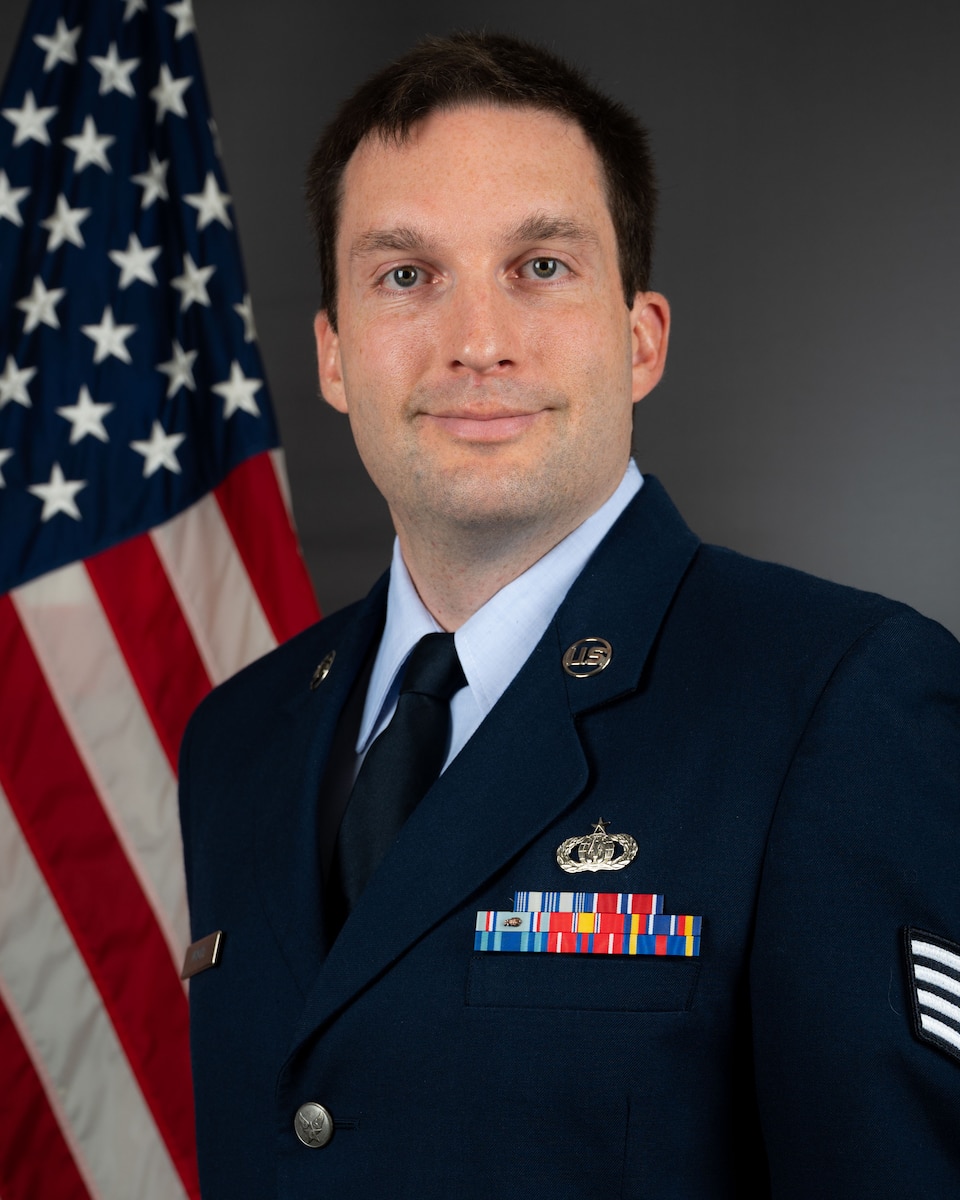 Official Photo of SSgt James Wright, trombonist with Heritage Brass and the Concert Band, two of six ensembles with the Heritage of America Band, Langley AFB, VA.  SSgt Wright is wearing blue service dress in front of the American flag.