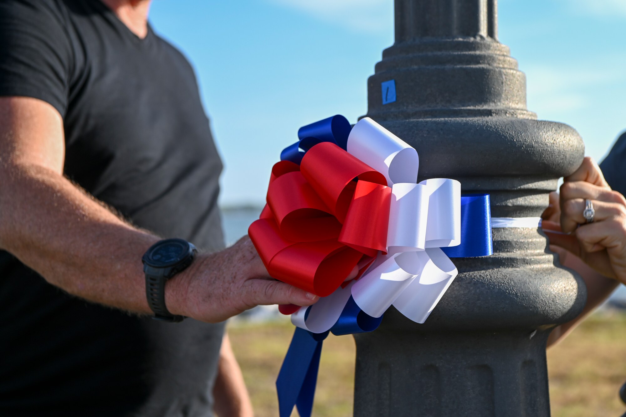 Volunteers place a ribbon on a lamp post during the Second Annual Memorial Day Remembrance event at MacDill Air Force Base, Florida, May 25, 2022.