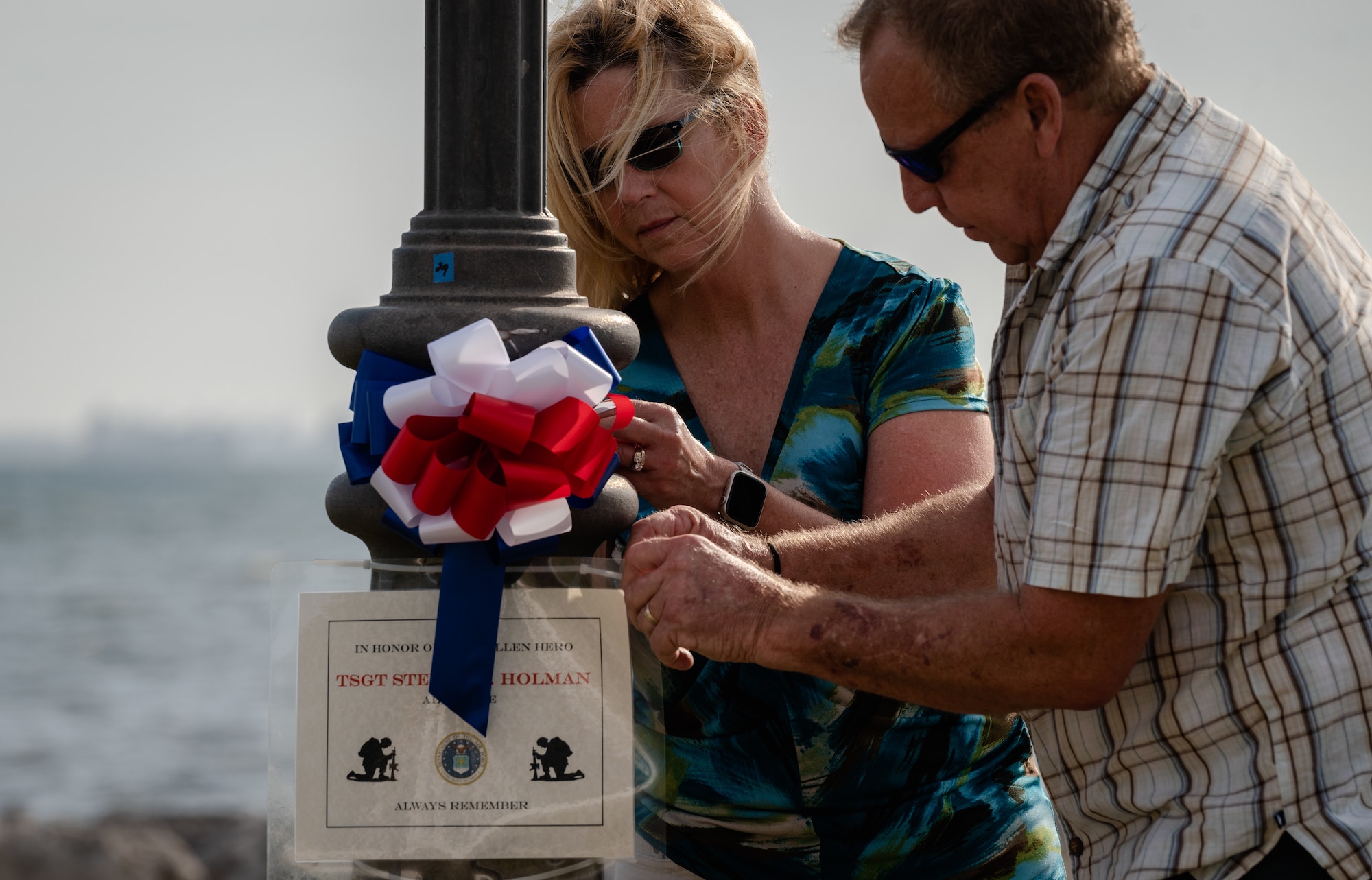 Mr. and Mrs. Holman, surviving family of Tech. Sgt. Steven Holman, place a memorial sign for their son on a lamp post at MacDill Air Force Base, Florida during the Second Annual Memorial Day Remembrance event May 25, 2022.