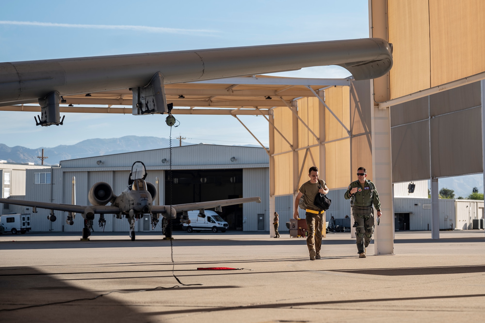 A photo of a pilot and a maintainer walking side by side on the flight line.